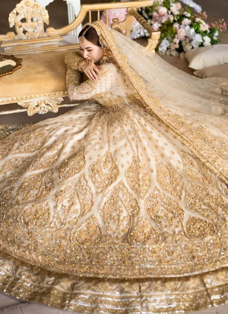 Pakistani ivory bridal lehenga with 14 kali flared silhouette, intricate gold embellishments and detailed embroidered hem border