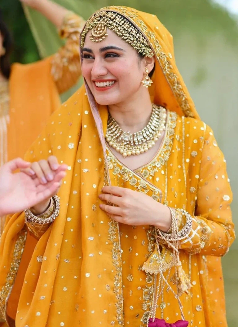 Pakistani yellow Mehndi Angrakha dress for bride with traditional embroidery and graceful silhouette