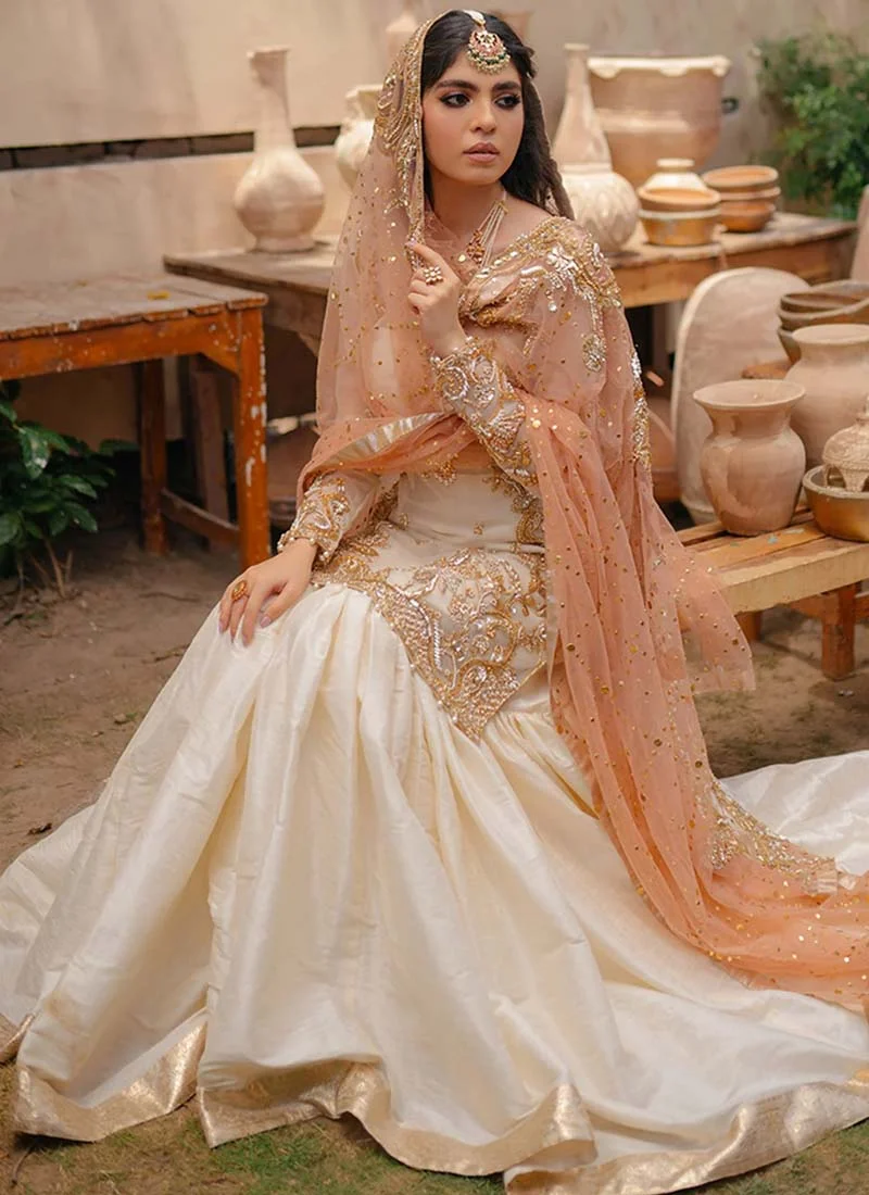 White bridal gharara with gold, rose-gold and silver embroidery framing the straight organza kameez and hem