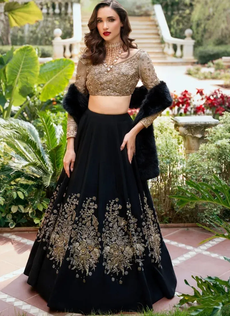 Black Walima Lehenga Choli with Oversized Gold Bouquets Black and gold bridal lehenga choli front view with floral skirt embroidery and black faux-fur stole