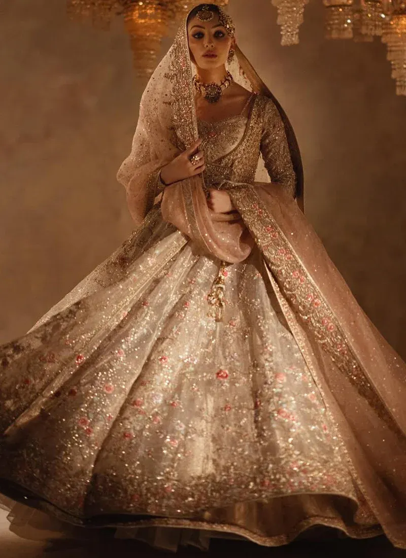 Champagne bridal angrakha and lehenga side view with sweeping embroidered hem and flowing pink dupatta