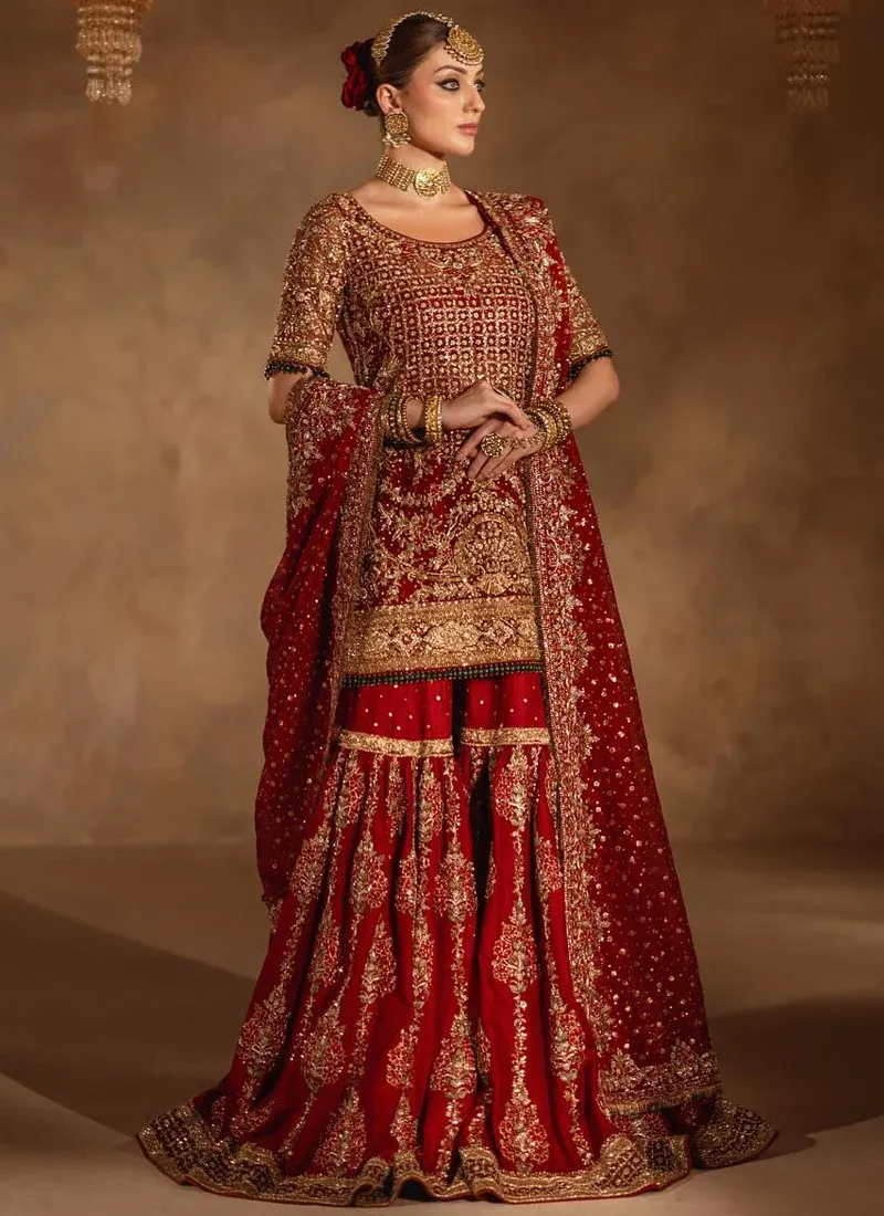 Deep red farshi gharara front view with gold floral panels and a matching sheer bordered dupatta.