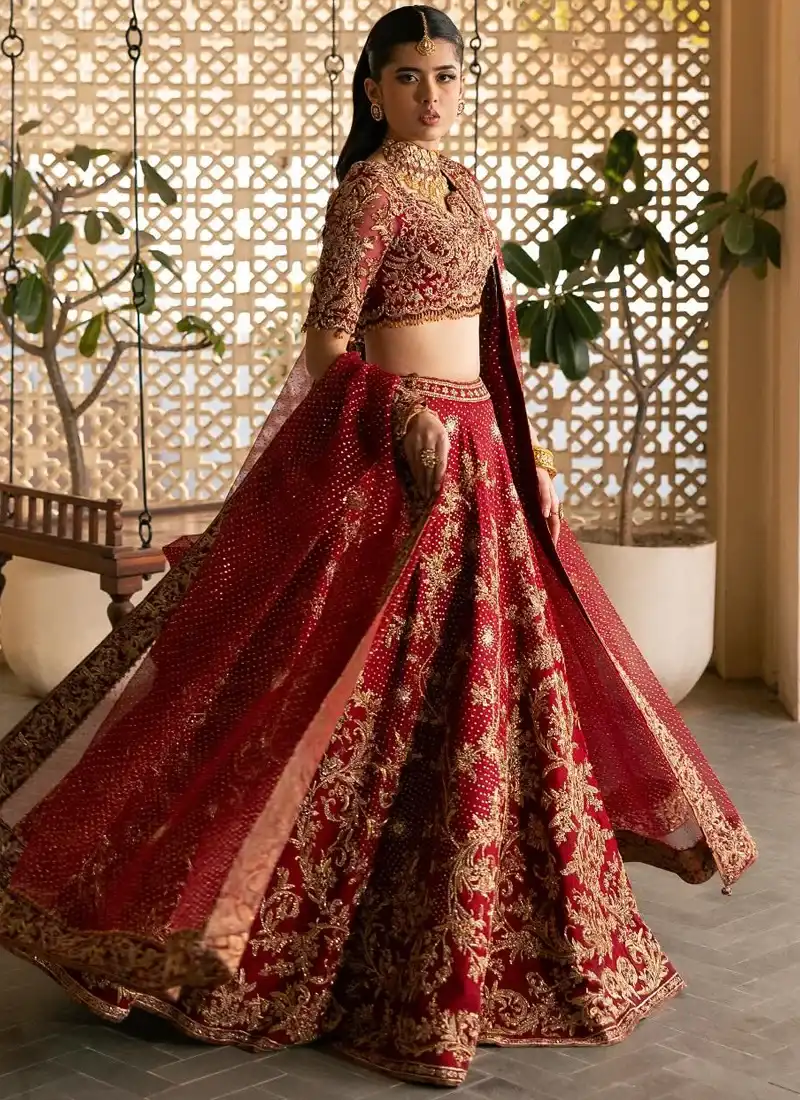 Deep red bridal lehenga choli in full-length rear view with sweeping gold floral embroidery across the flared skirt