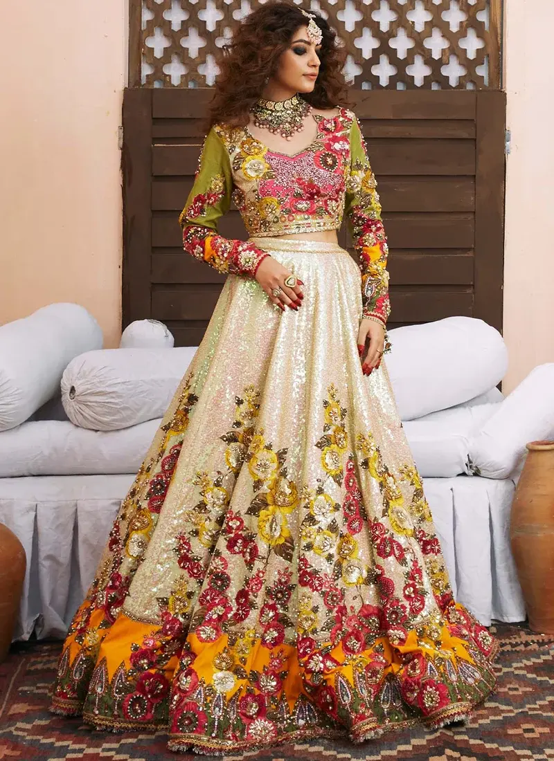 Ivory floral bridal lehenga seated view with sheer gold-sequinned dupatta and ornate multicolour border