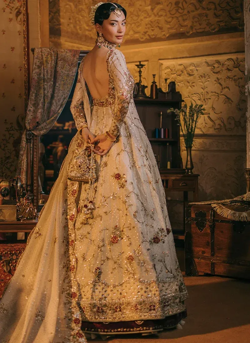 Ivory open gown and lehenga from the back, showing a deep scooped neckline and richly embroidered flared hem