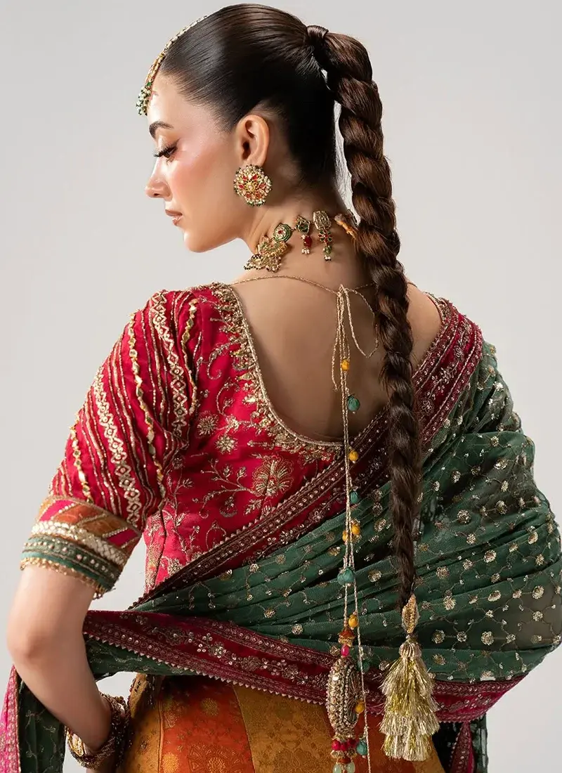 Orange Mehndi lehenga choli in seated view with a pink floral blouse and sheer green sequinned dupatta