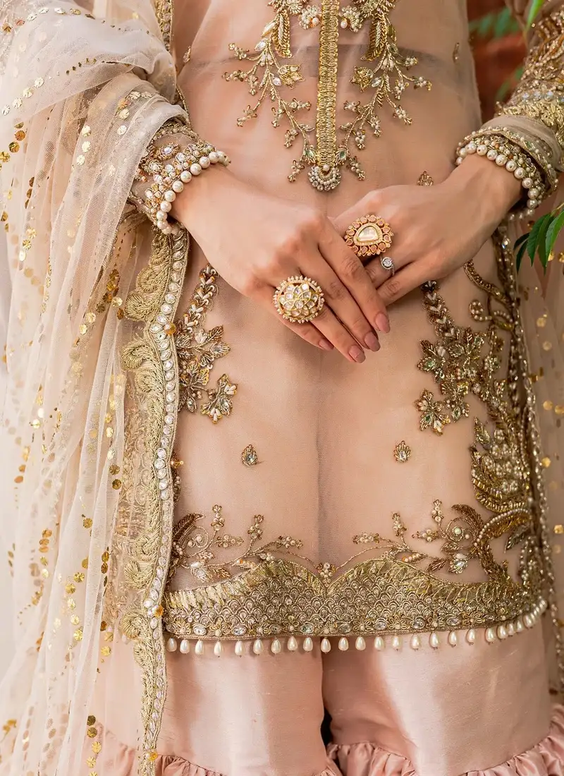 Peach gharara shirt close-up showing a round neckline, symmetrical gold embroidery and sheer lattice sleeves