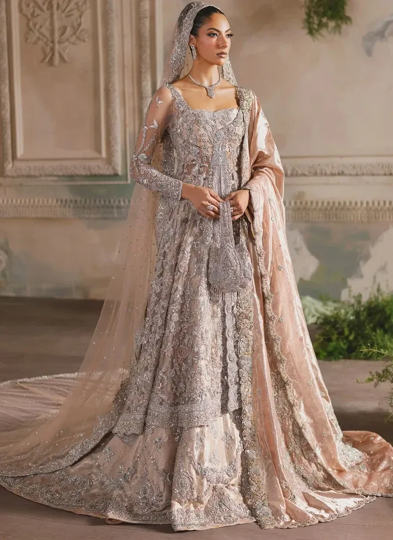 Peach Walima Farshi Lehenga with Sweeping Back Train Peach bridal farshi lehenga side view beneath a sheer net veil with a wide embroidered border