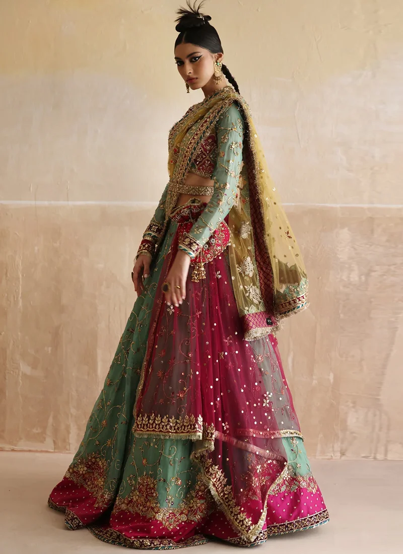 Sea green lehenga choli side view with hot pink embroidered hem and sheer yellow dupatta