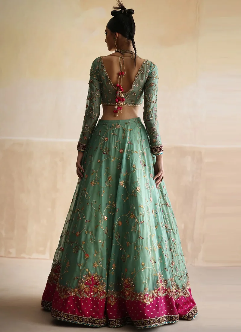 Sea green lehenga choli back view with deep V tie-back, pink tassels and embroidered hem