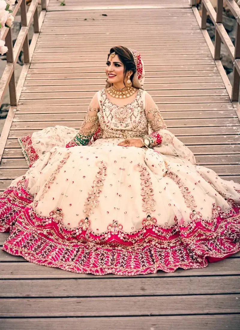 White Nikkah gown, standing three-quarter view with sweeping skirt and ornate pink embroidered border