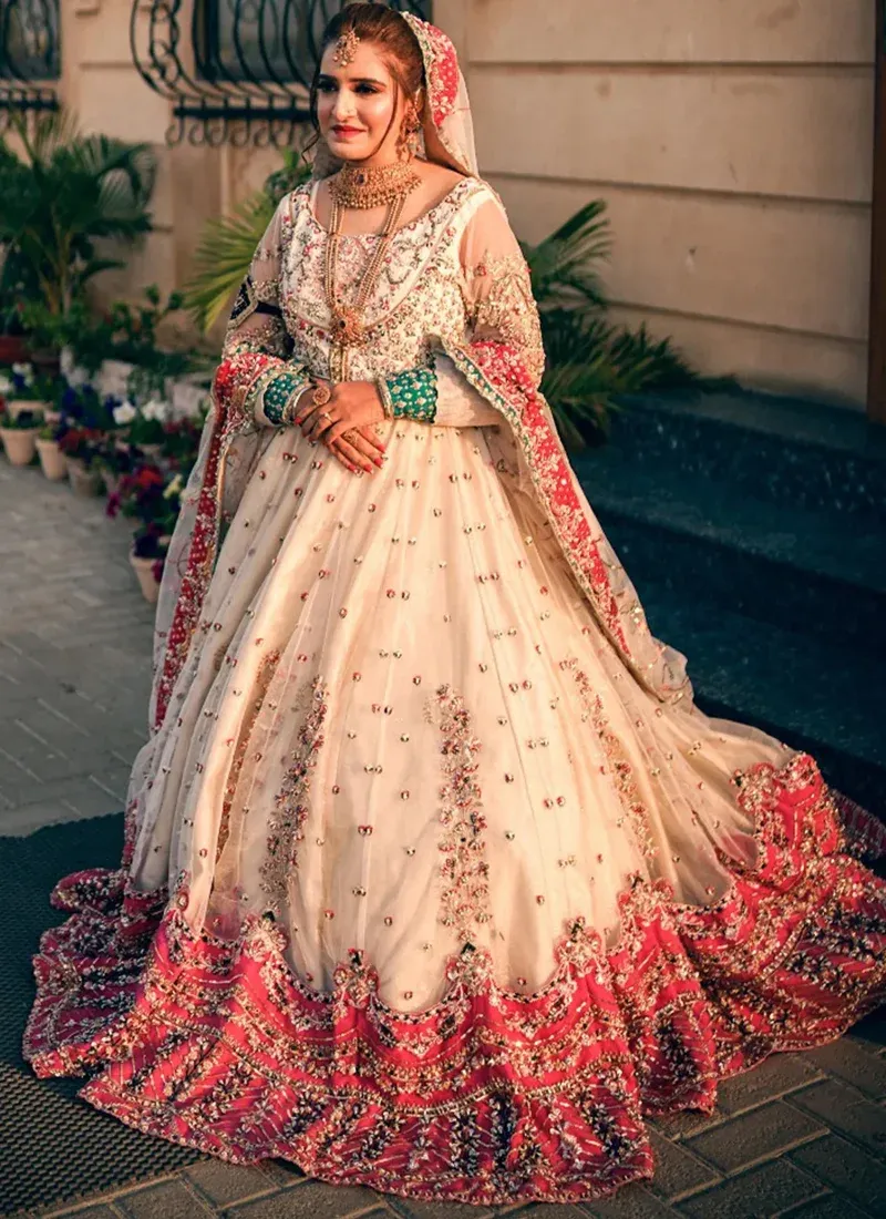 White and pink bridal gown, front view with sheer floral dupatta and repeating embroidered skirt motifs